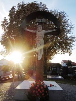 Friedhofskreuz mit Sonne im Hintergrund